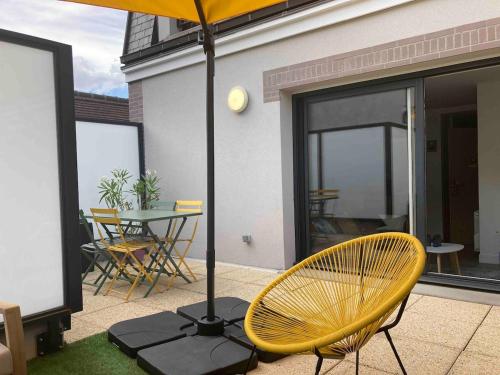 Una silla amarilla y una sombrilla en un patio. en Appartement terrasse entre Paris et Disney, en Bry-sur-Marne