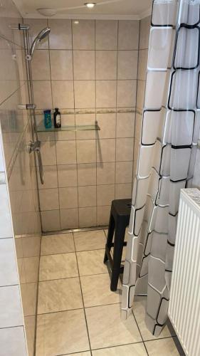La salle de bains est pourvue d'une douche avec un tabouret noir. dans l'établissement La maison de Lilly - meublé de tourisme 4 étoiles, à Zilling