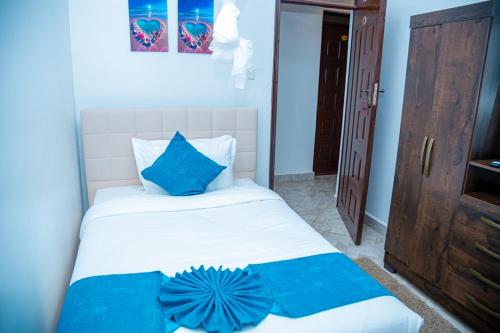 a bedroom with a bed with blue pillows on it at The lit garden place in Kisumu