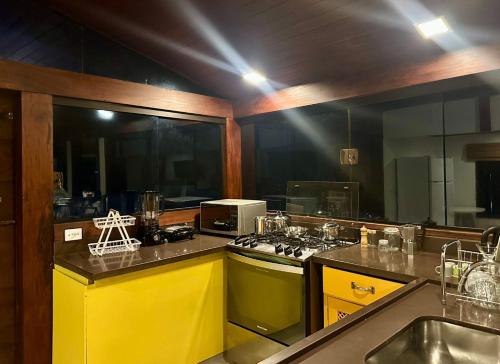 a kitchen with yellow cabinets and a stove top oven at Pousada Sambaki in Paraty