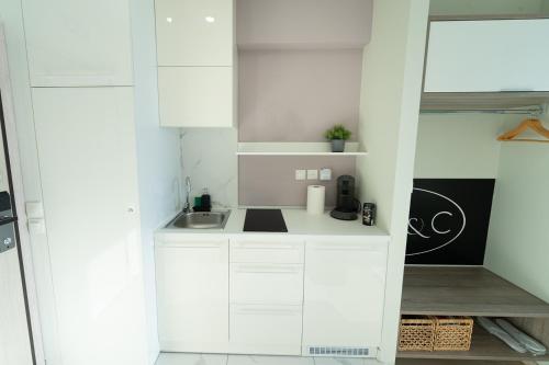 a small kitchen with white cabinets and a sink at Sea & the City in Thessaloniki