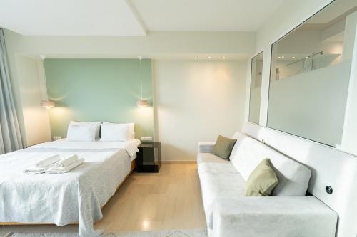 a bedroom with a white bed and a couch at Sea & the City in Thessaloniki