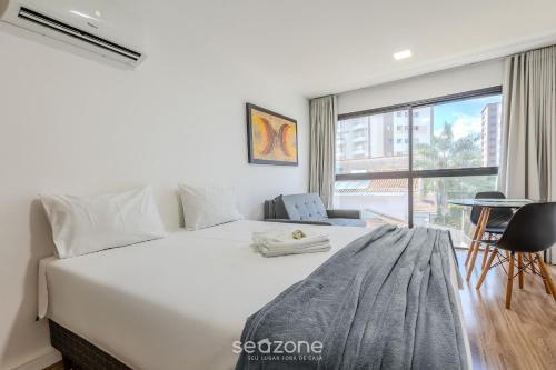 a bedroom with a large white bed and a window at Studio c/ piscina em Poços de Caldas PGO412 in Poços de Caldas