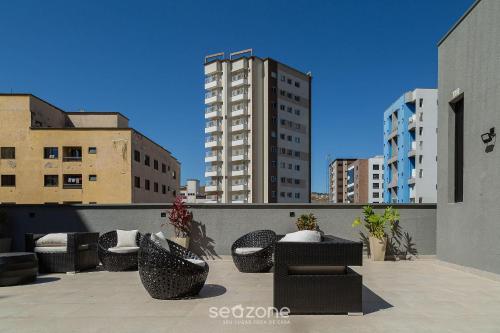 a patio with couches and chairs on a balcony with buildings at Studio c/ piscina em Poços de Caldas PGO412 in Poços de Caldas