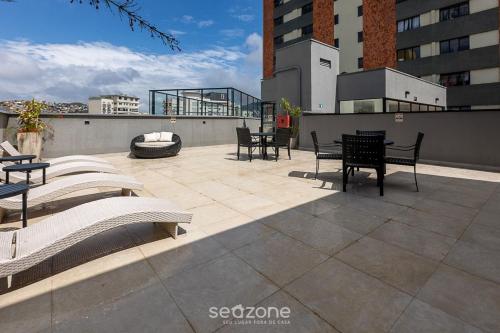 a patio with chairs and tables on top of a building at Studio c/ piscina em Poços de Caldas PGO412 in Poços de Caldas