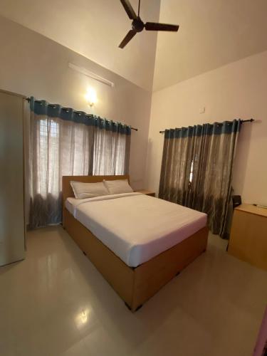 a bedroom with a bed and a ceiling fan at Berghof villa Rooms in Cochin