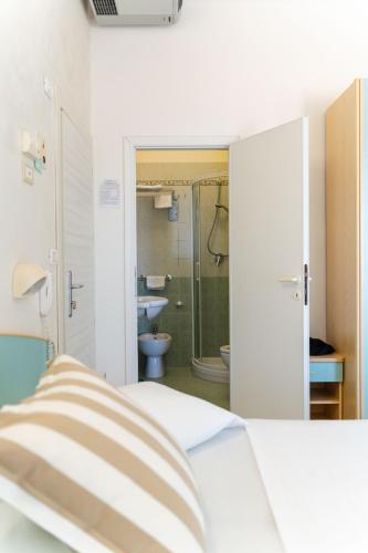 a bedroom with a bed and a bathroom with a shower at Strand Hotel in Gabicce Mare