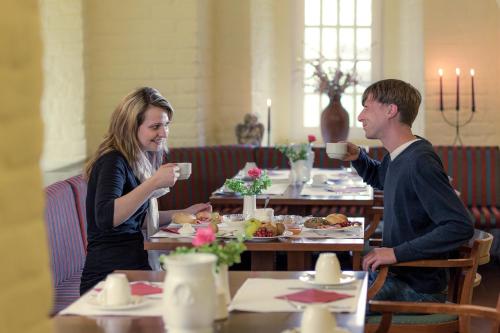 a man and a woman sitting at a table drinking coffee at Hotel Schloss Neustadt-Glewe in Neustadt-Glewe