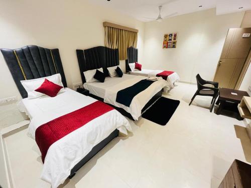 a bedroom with two beds with red and white sheets at Hotel Royal Sky in Morbi