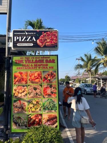 a woman standing next to a sign that says pizza at Cha-am , Twin Bed Room , Naer Cha-am Beach South in Ban Bo Khaem