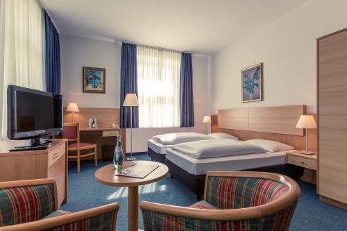 a hotel room with a bed and a tv and chairs at Hotel Schloss Neustadt-Glewe in Neustadt-Glewe