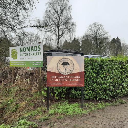 two signs on a sidewalk next to a hedge at Stacaravan in De Pol