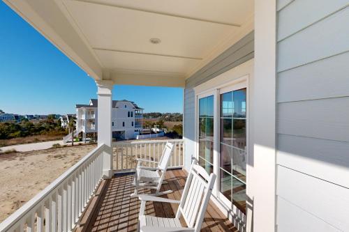 a porch with two chairs on the beach at Beach Hunters in Holden Beach