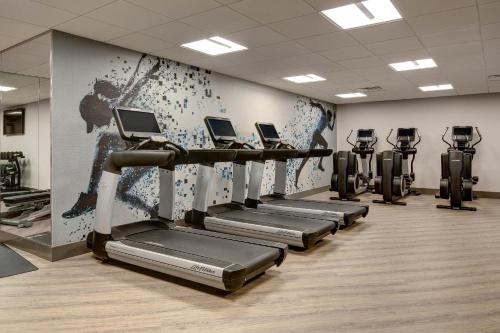 a gym with rows of tread machines and a wall at Sheraton Eatontown Hotel in Eatontown