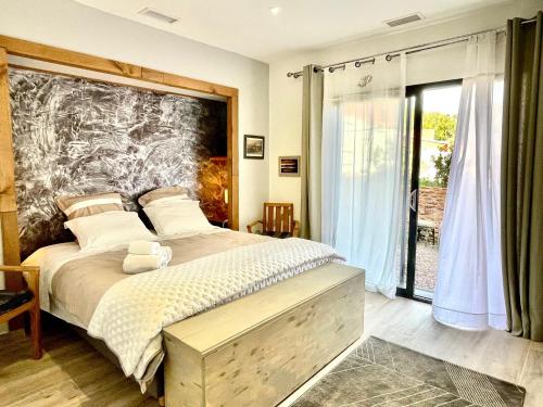 une chambre avec un grand lit et une grande fenêtre dans l'établissement Les Terres Rouges du Salagou, à Le Bosc