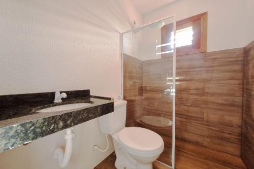 a bathroom with a toilet and a glass shower at The Point Bangalô Pé na Areia em Fortim in Fortim