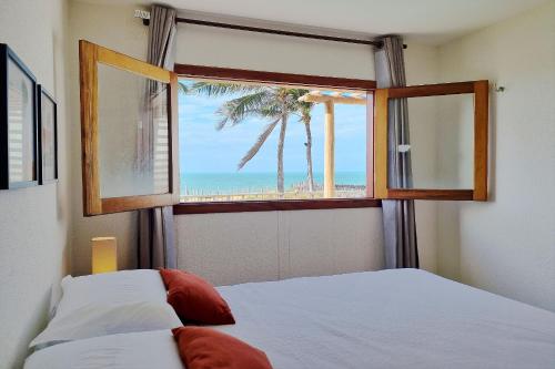 a bedroom with a window with a view of the beach at The Point Bangalô Pé na Areia em Fortim in Fortim