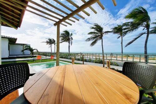 a wooden table with chairs and a view of the ocean at The Point Bangalô Pé na Areia em Fortim in Fortim