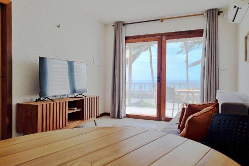 a living room with a flat screen tv and a wooden table at The Point Bangalô Pé na Areia em Fortim in Fortim