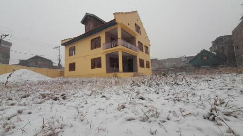 a yellow house in a field with snow on it at Khadim Villa & Travel Planners in Srinagar