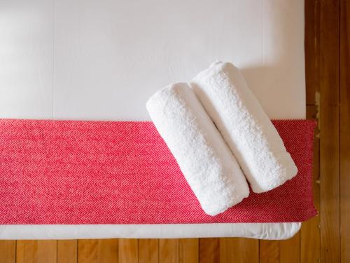 dwa białe ręczniki siedzące na czerwonej macie w obiekcie Montacute Boutique Bunkhouse w mieście Hobart