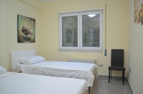 two beds in a room with a window and a chair at Home Sweet Home by the Sea - 060 in Durrës