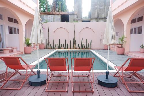 a pool with chairs and umbrellas on a patio at Ponder Bali Canggu in Canggu