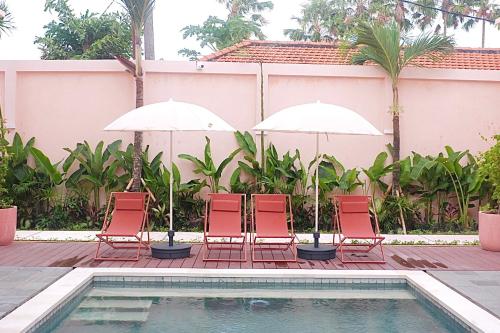 a group of chairs and umbrellas next to a pool at Ponder Bali Canggu in Canggu