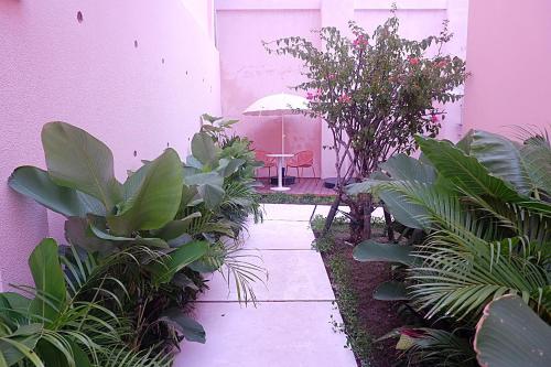 a garden with a table and a chair in a pink building at Ponder Bali Canggu in Canggu
