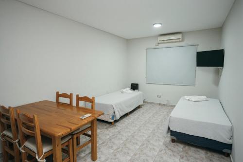 a room with two beds and a table and a whiteboard at PM departamentos in San Rafael