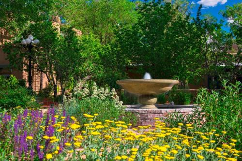 a fountain in the middle of a garden with flowers at La Posada De Santa Fe, a Tribute Portfolio Resort & Spa in Santa Fe