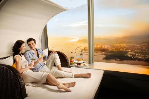 a man and a woman sitting on a plane with wine glasses at The Ritz-Carlton, Hong Kong in Hong Kong