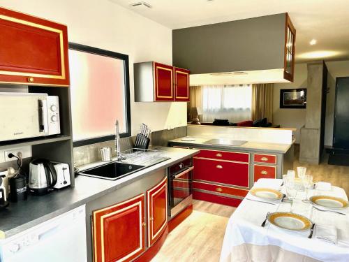 - une cuisine avec des placards rouges et une table dans l'établissement Les Terres Rouges du Salagou, à Le Bosc