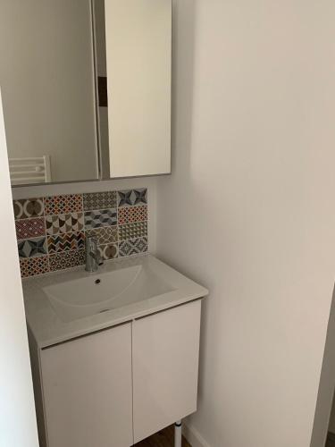 une salle de bain blanche avec un lavabo et un miroir dans l'établissement Maison de bourg, aux Épesses