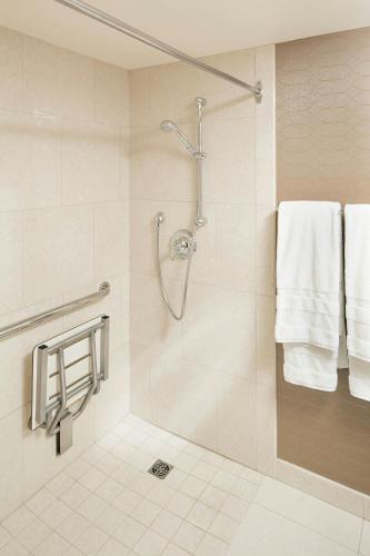 a bathroom with a shower with white towels at Sheraton Cavalier Calgary Hotel in Calgary