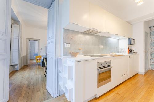 une cuisine avec des armoires blanches et un four à plaques de cuisson dans l'établissement Esprit Feydeau- Appartement de charme en hypercentre de Nantes, à Nantes