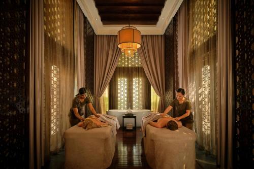 two people laying in beds in a hotel room at The Ritz-Carlton Ras Al Khaimah, Al Wadi Desert in Ras al Khaimah