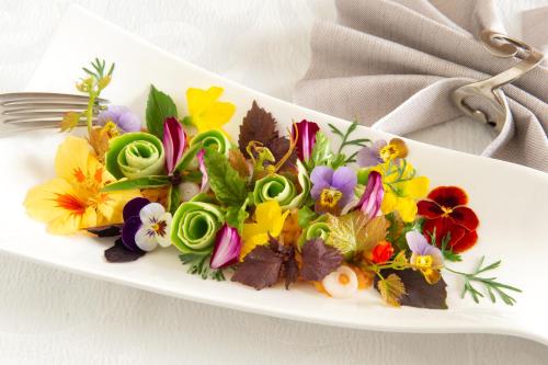 a white plate topped with colorful flowers on a table at lO GORISSADO - La ferme du glandier in Saint-André-dʼAllas