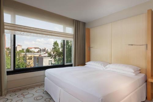 a bedroom with a large white bed and a large window at Sheraton Berlin Grand Hotel Esplanade in Berlin