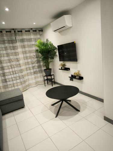 un salon avec une table et une télévision dans l'établissement Petit Lenny, à Oissel