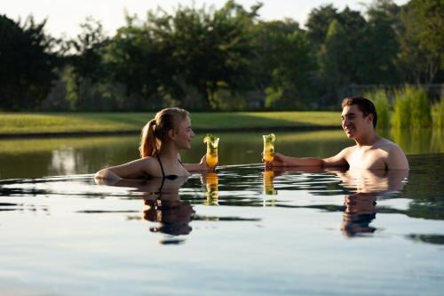 a man and woman in the water with beer at Le Meridien Chiang Rai Resort, Thailand in Chiang Rai