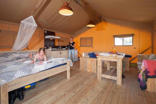 Ein kleines Mädchen, das in einem Zimmer auf einem Bett liegt. in der Unterkunft Glamping Rhederlaagse Meren in Lathum
