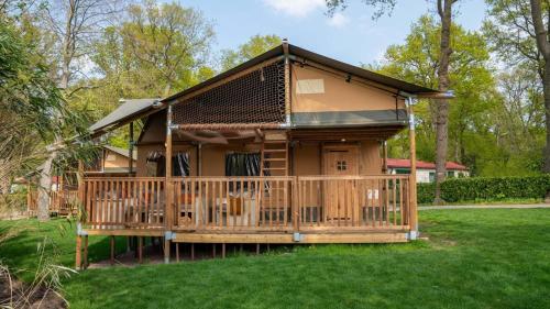 a large wooden house with a large deck at Glamping Rhederlaagse Meren in Lathum