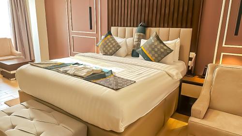 a hotel room with a large bed and a chair at Tribu Hotels in Enugu