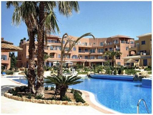 a resort with a swimming pool and palm trees at H&O Limnaria Elegance Pool View Apartment in Paphos City