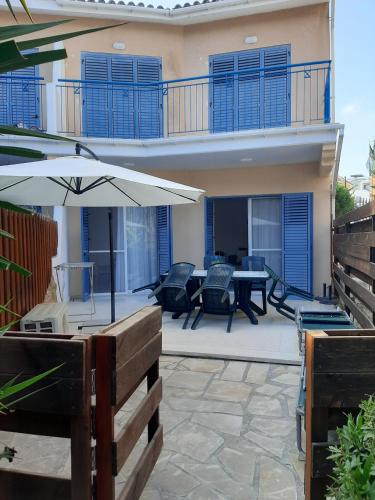 a patio with an umbrella and a table and chairs at H&O Elegant Maisonette in Paradise Garden in Paphos