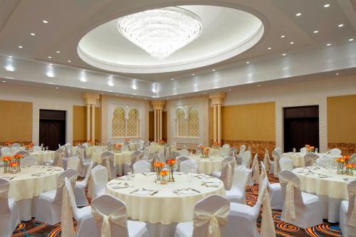 a banquet hall with white tables and chairs and a chandelier at Sheraton Sharjah Beach Resort and Spa in Sharjah