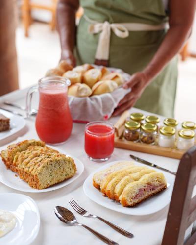 a table with cakes and pastries on plates and a person at Casa Poema Paraty in Paraty