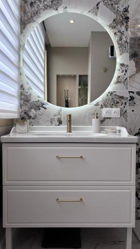 une salle de bain avec un lavabo blanc et un miroir dans l'établissement JARDIN TERRASSE EDEN SAINT TROPEZ - Parking Pool AC 4P, à Saint-Tropez