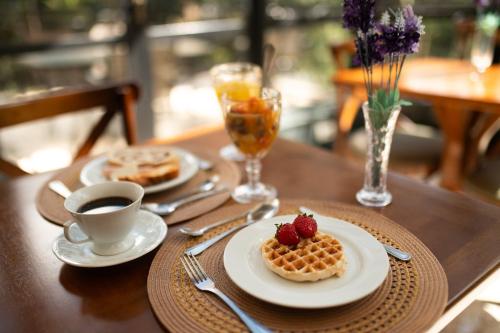 a table with two plates of waffles and a cup of coffee at Araucária Lodge - 800 metros do Capivari in Campos do Jordão